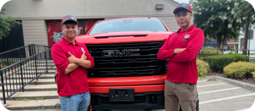 two employees standing in front of a red work truck
